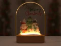 Lampka LED dla dzieci z motywem Merry Christmas, przedstawiająca świąteczną scenę z Mikołajem, bałwanem i choinką, doskonała jako personalizowany prezent na Boże Narodzenie oraz ciepła dekoracja do pokoju malucha.