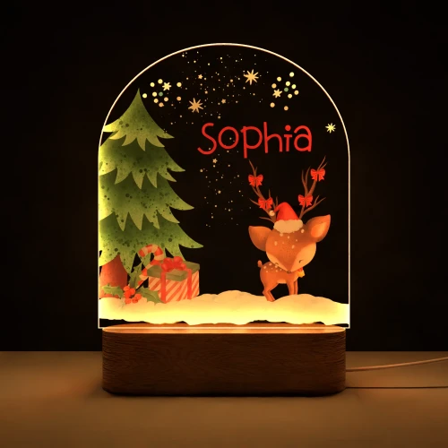 Personalizowana lampka LED dla dzieci ze świąteczną sceną przedstawiającą uroczą sarenkę w czapce Mikołaja, ozdobioną choinkę i prezenty w śnieżnym krajobrazie, idealna na prezent świąteczny oraz dekorację pokoju dziecka.