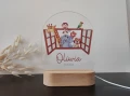Urocza lampka LED dla dzieci z otwartym oknem i wesołymi zwierzątkami, na drewnianej podstawce, personalizowana z imieniem dziecka, idealna do pokoju niemowlaka lub jako wyjątkowy prezent na narodziny.