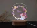 Lampka nocna LED z uroczym jednorożcem otoczonym gwiazdkami i balonikami, świetnie sprawdzi się jako subtelne źródło światła oraz dekoracja w dziecięcym pokoju.
