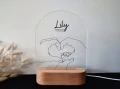Lampka LED dla dziecka z konturowym wzorem dłoni rodziców tworzących serce wokół stópek dziecka, doskonała jako pamiątka narodzin lub dekoracja do pokoju malucha.