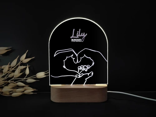 Personalizowana lampka LED z motywem stópek dziecka otoczonych kwiatowym wieńcem, idealna jako dekoracja pokoju dziecięcego lub prezent na chrzciny.