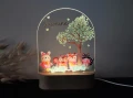 Oświetlana lampka LED dla dziecka z kolorową grafiką leśnych zwierząt i drzewem w tle, tworząca przytulną atmosferę w dziecięcym pokoju.