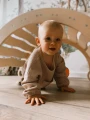 Uśmiechnięte niemowlę bawi się pod drewnianym bujakiem Montessori 90 cm.