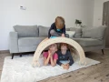 Troje dzieci bawi się pod bujakiem Montessori 90 cm ustawionym jako tunel.