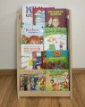 Front regału Montessori pełnego książek dla dzieci – naturalna sklejka, ergonomiczny design i swobodny dostęp do bajek.