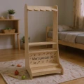 Stojak do zabawy w sklep dla dzieci inspirowany metodą Montessori, wykonany z jasnej sklejki, z półkami na zabawkowe produkty i ladą dla małego sprzedawcy.