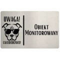 Tabliczka z grafiką psa w okularach i napisem „Obiekt monitorowany”.