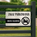 Ciemna tabliczka z napisem o zakazie parkowania na prywatnej posesji.