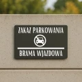 Tabliczka zakazująca parkowania zamontowana na płocie.