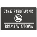 Tablica informacyjna z zakazem parkowania przy wejściu do budynku mieszkalnego.